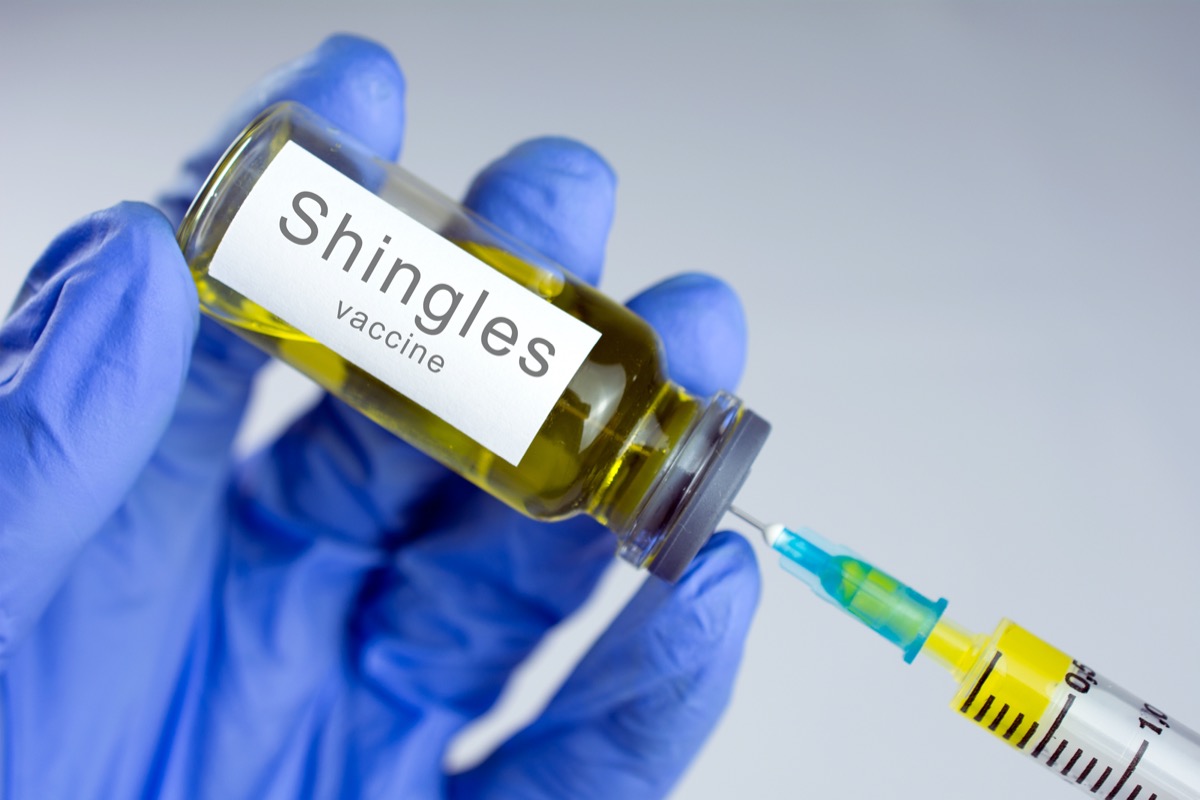 Hands in blue gloves are typing a yellow vaccine in a syringe