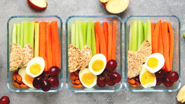 Healthy snack meal prep with cut carrots celery hard boiled eggs apples grape almonds and rice cakes