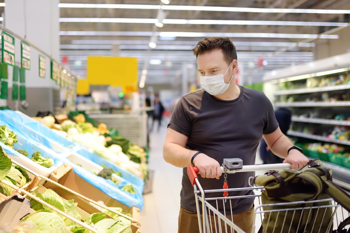 Man wearing disposable medical mask shopping in supermarket during coronavirus pneumonia outbreak