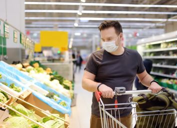 Man wearing disposable medical mask shopping in supermarket during coronavirus pneumonia outbreak