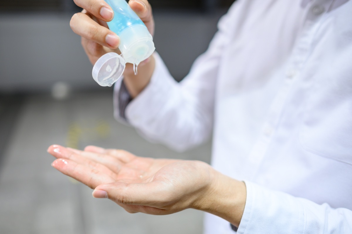 Male hand using hand skin sanitizer gel tube for washing hand at subway station. Health awareness for pandemic protection