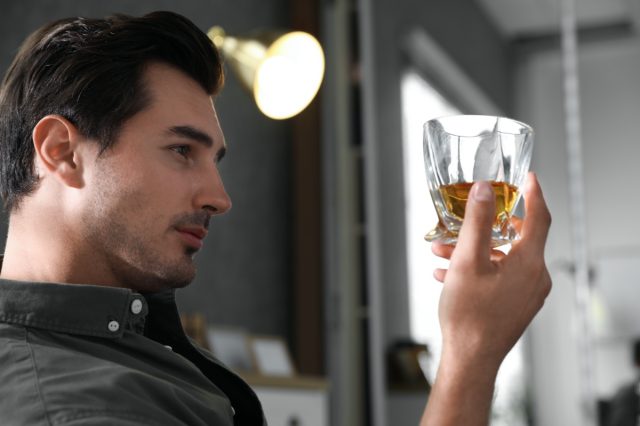 man with glass of whiskey at home