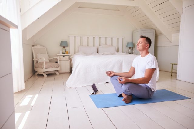 Mature man with digital tablet with bedroom meditation app
