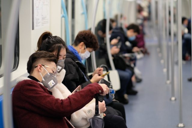 People wearing surgical masks sit on the subway in Shanghai