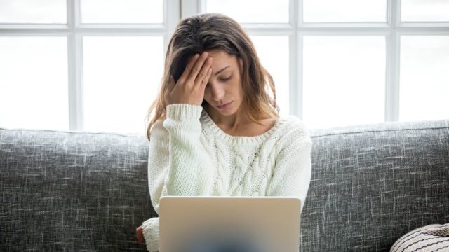Frustrated sad woman feeling tired worried about problem sitting on sofa with laptop, stressed depressed girl troubled with reading bad news online, email notification about debt or negative message