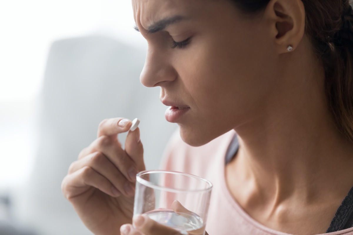 Unhappy woman side view holds tablet and glass of water