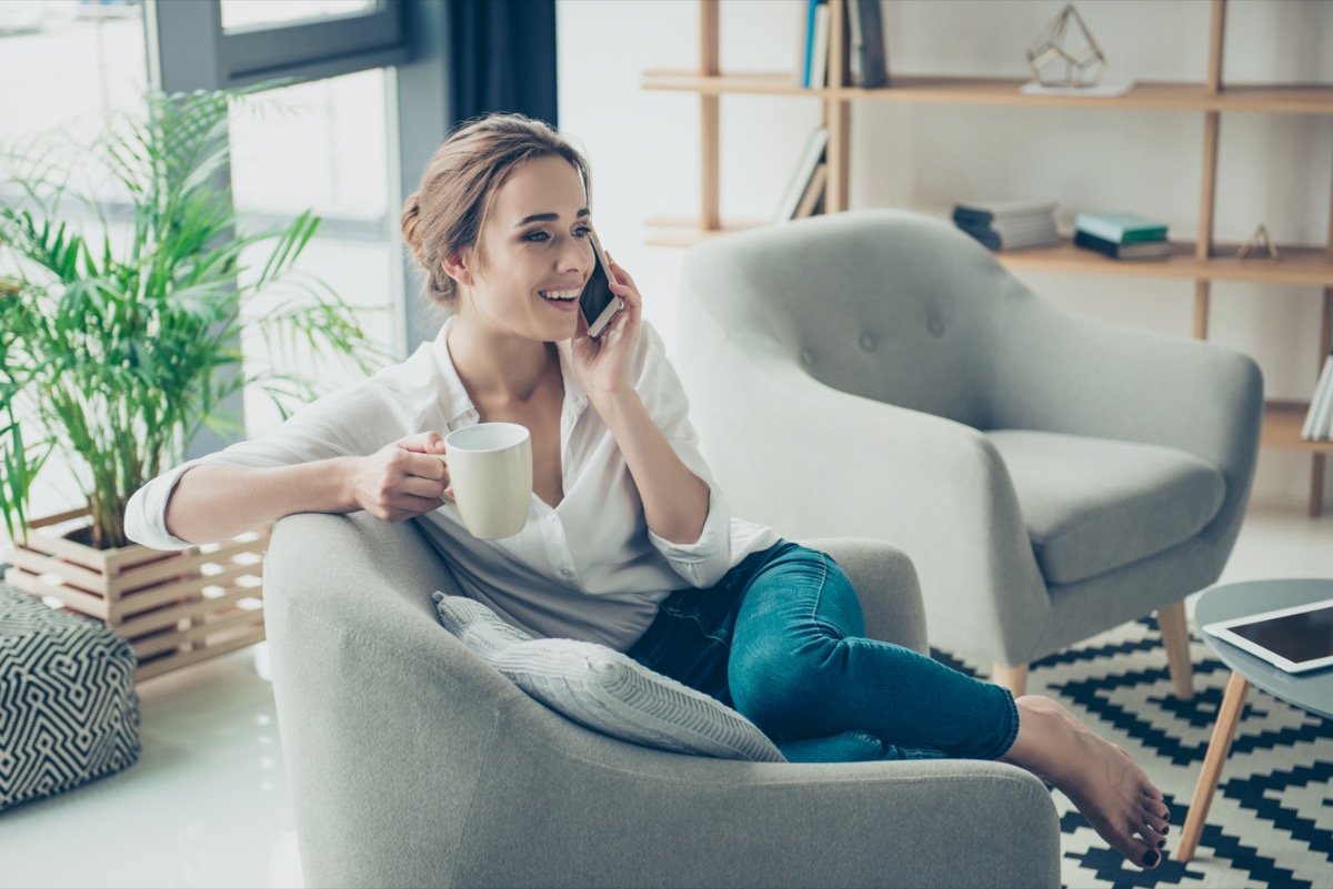 is chatting on her telephone, sitting on armchair