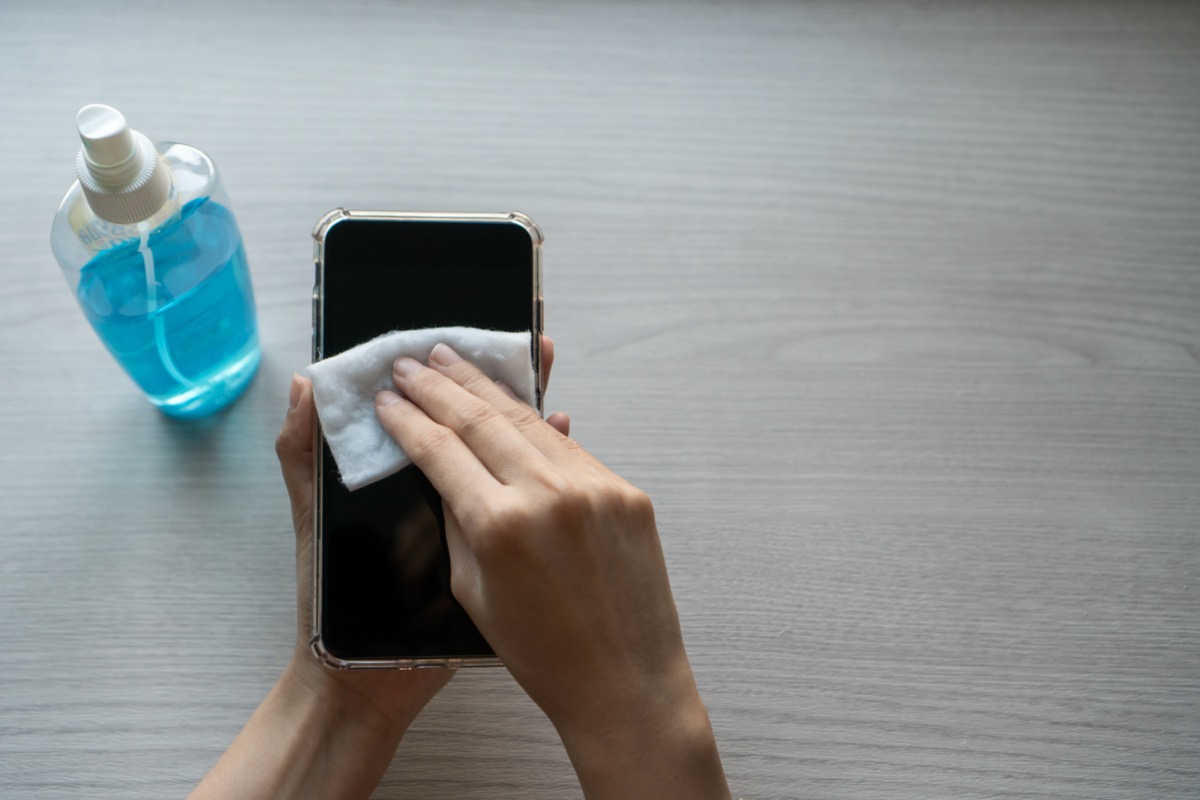 Hand of Woman cleaning smartphone screen with alcohol, prevent infection of Covid-19 virus, contamination of germs or bacteria, wipe or cleaning phone to eliminate, outbreak of Coronavirus.