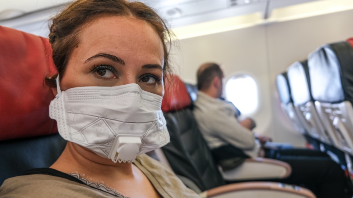 Woman Traveling with Plane with a Mask on For Contagious Disease
