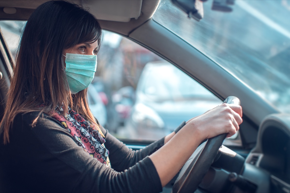 woman driving car with face mask