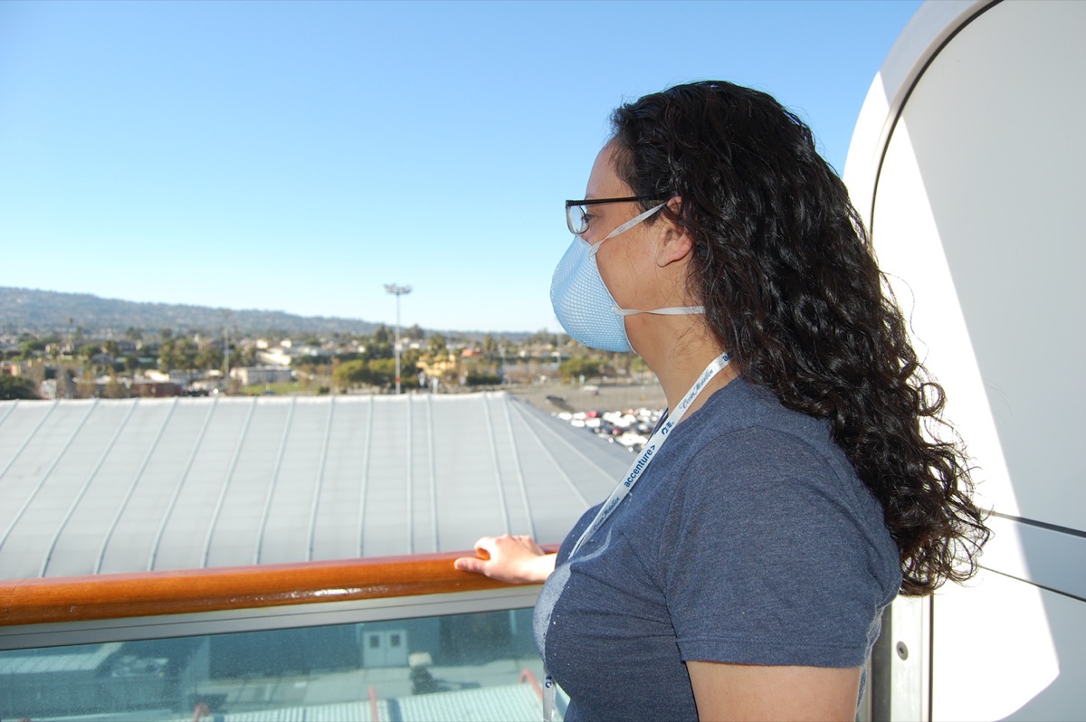 Woman on the balcony of her cabin on a Princess Cruise Ship wearing a surgical mask to prevent Coronavirus, flu or other infectious disease