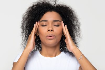 Nervous african woman breathing calming down relieving headache or managing stress, black girl feeling stressed self-soothing massaging temples exhaling