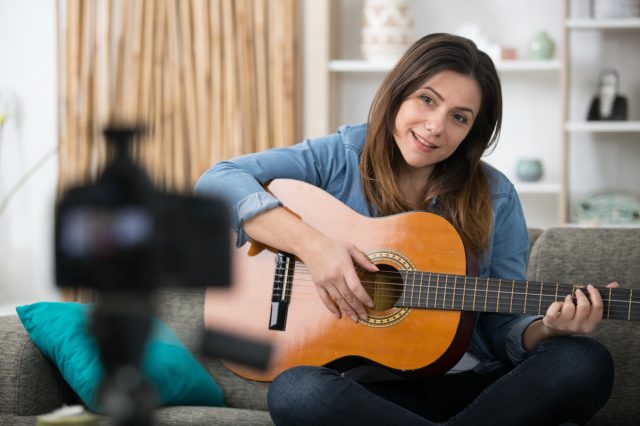 woman records a music blog with guitar