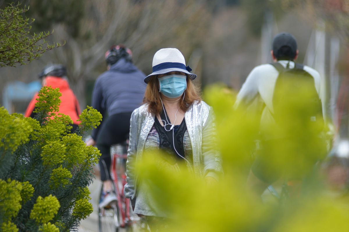 A woman wearing protective face mask is seen walking in the park during COVID-19 virus outbreak
