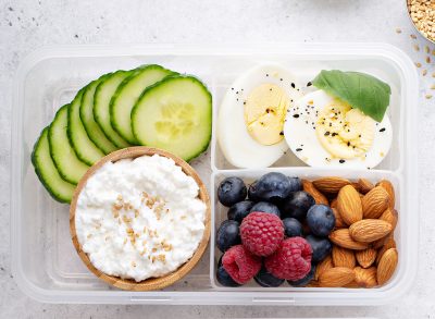 Breakfast bento box high protein with hard boiled eggs fruit nuts cottage cheese cucumber
