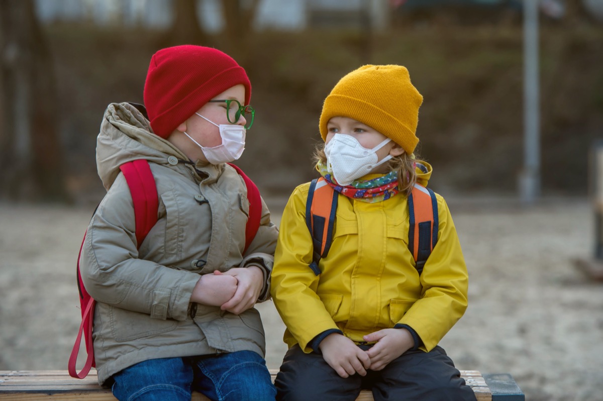 Child boy and girl playing outdoors with face mask protection. School boy breathing through medical mask