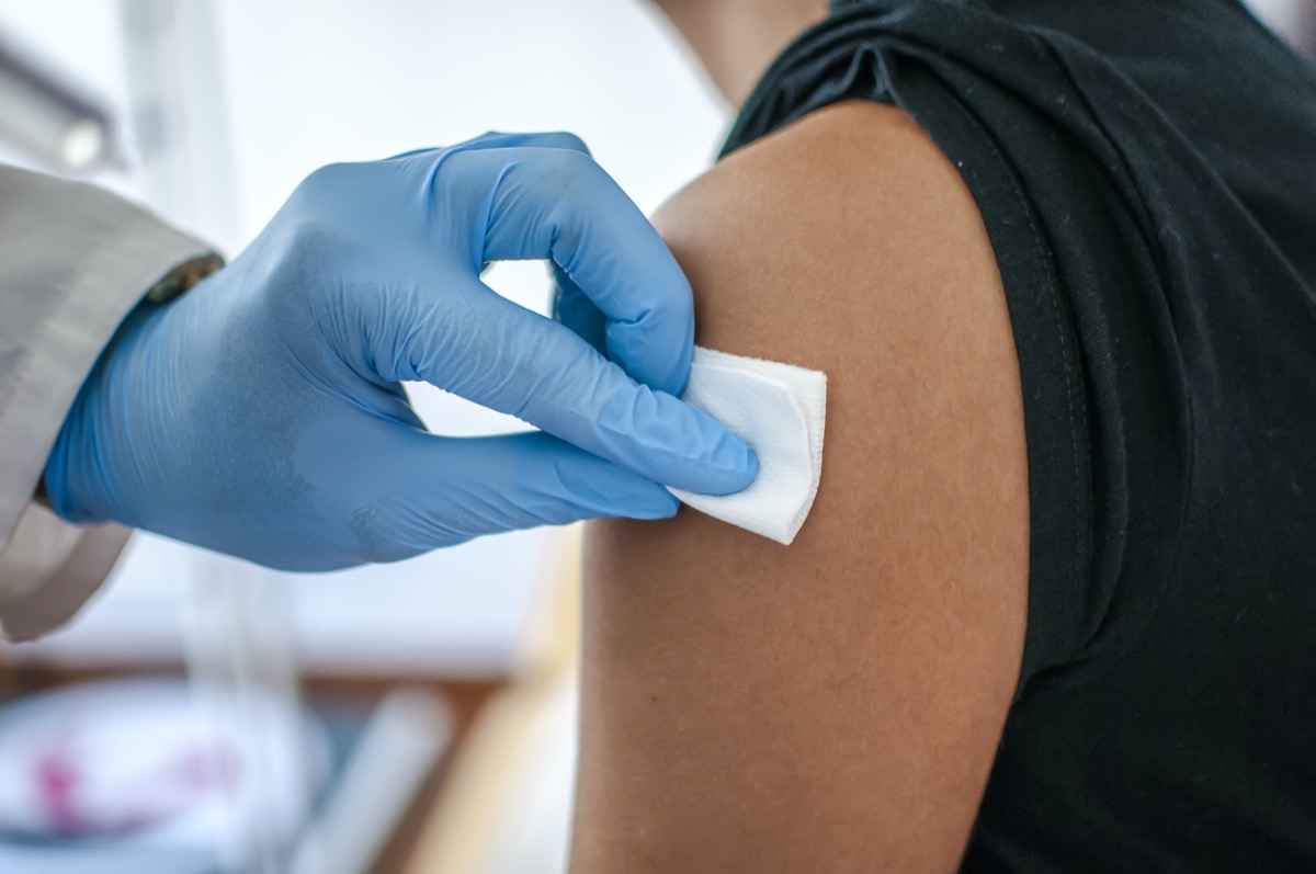 Doctor disinfects skin of patient before vaccination