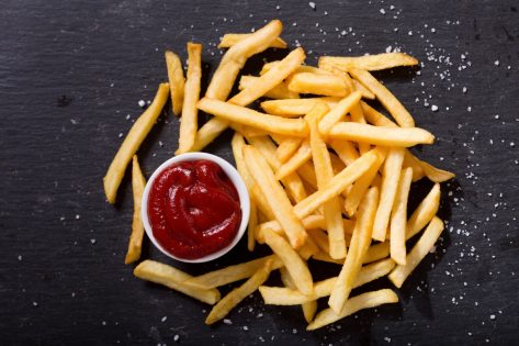 French fries with ketchup on dark background, top view