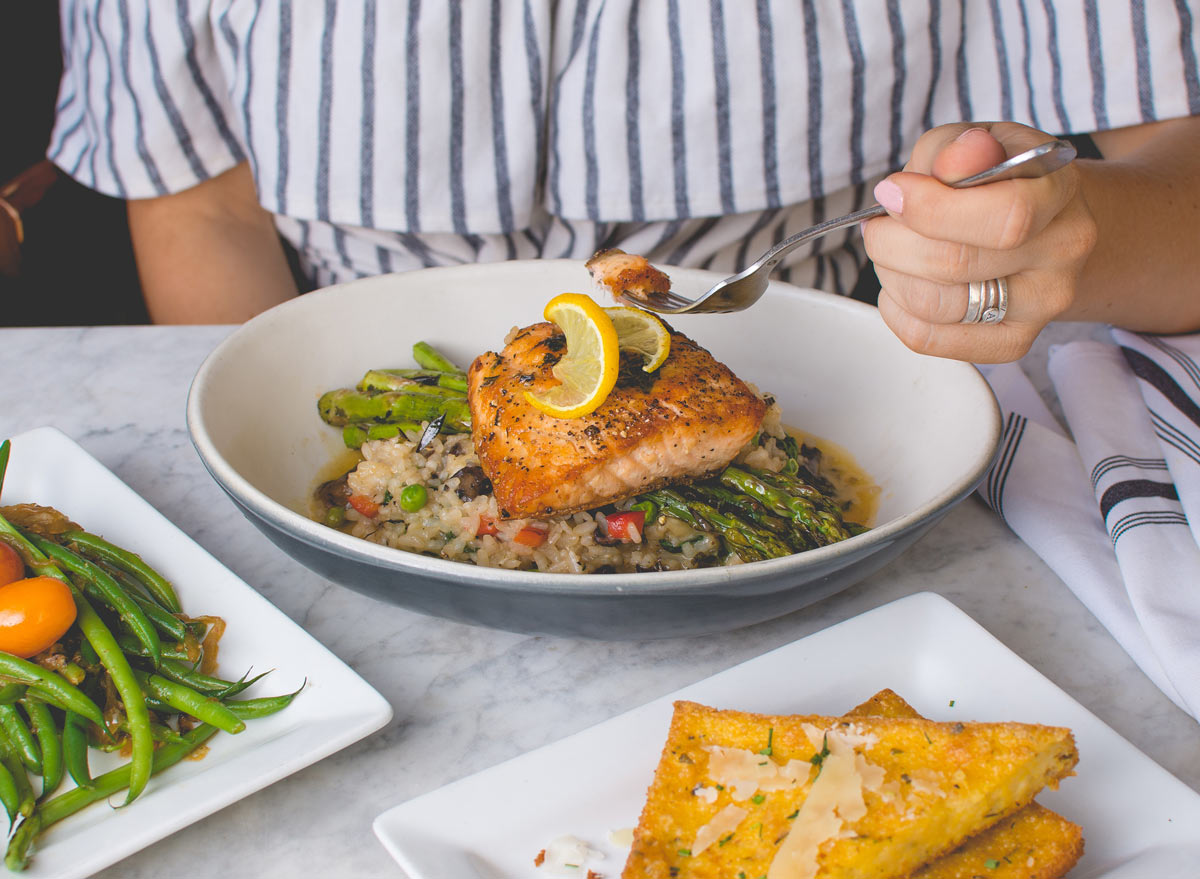 eating a bite of salmon with asparagus