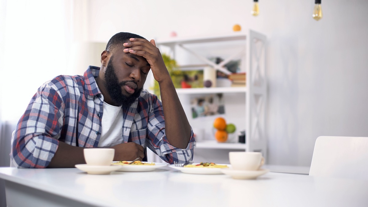Tired African-American man having headache after hard day, feeling exhausted