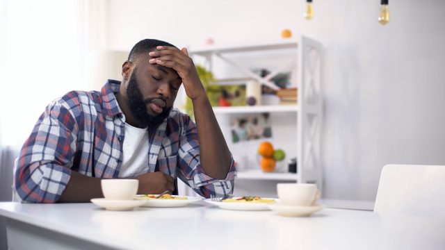 Tired African-American man having headache after hard day, feeling exhausted