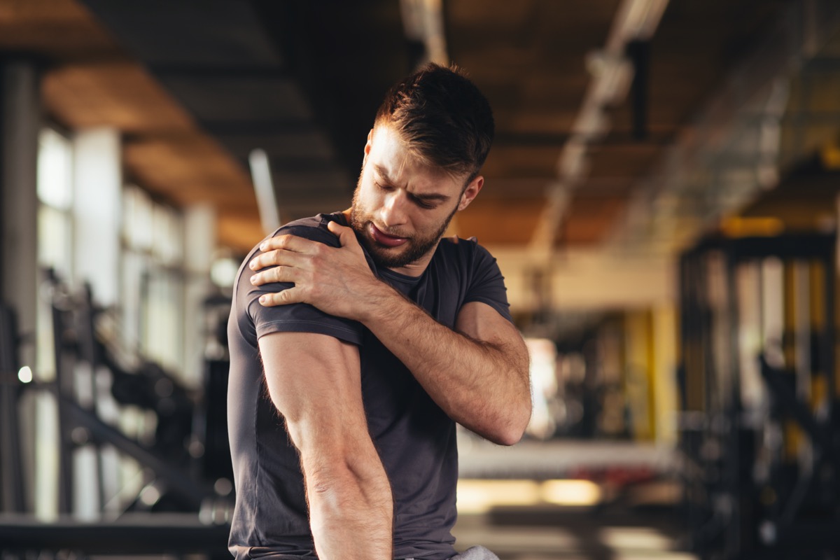 man feeling the pain in shoulder at the gym