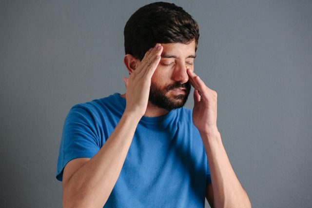 man holding his nose because sinus pain