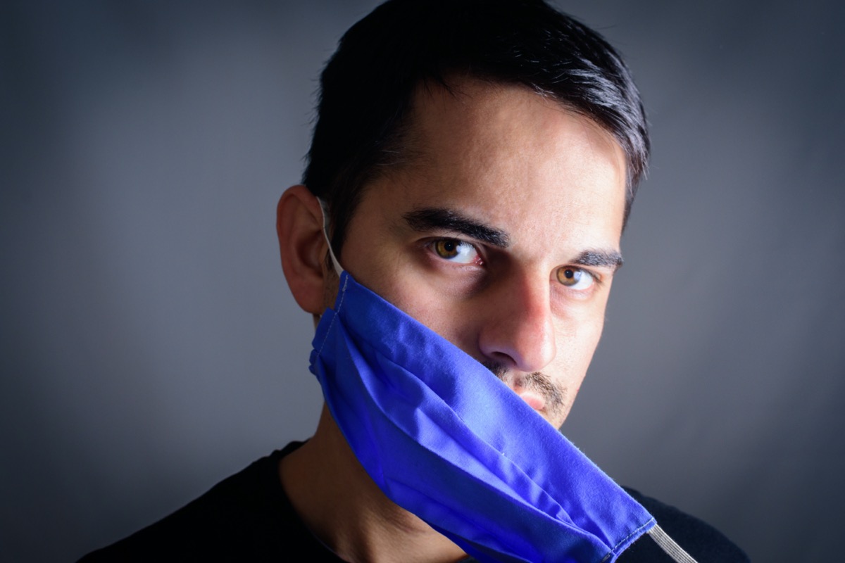  Man taking off mask with protective mask on face against Coronavirus