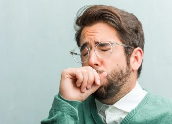 man face closeup with a sore throat, sick due to a virus, tired and overwhelmed