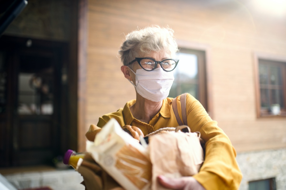 A senior woman wearing an outdoor face mask with the concept of shopping, corona virus and quarantine.