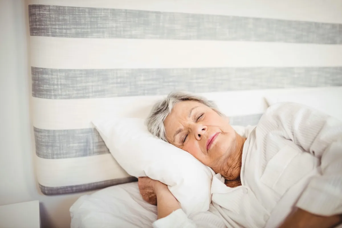 Senior woman sleeping on bed in bedroom