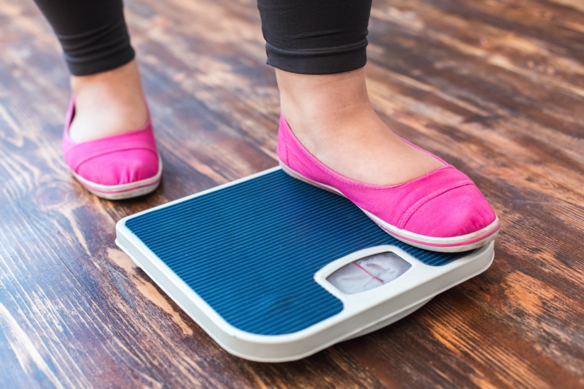 Chubby woman sport at home standing on scales checking weight