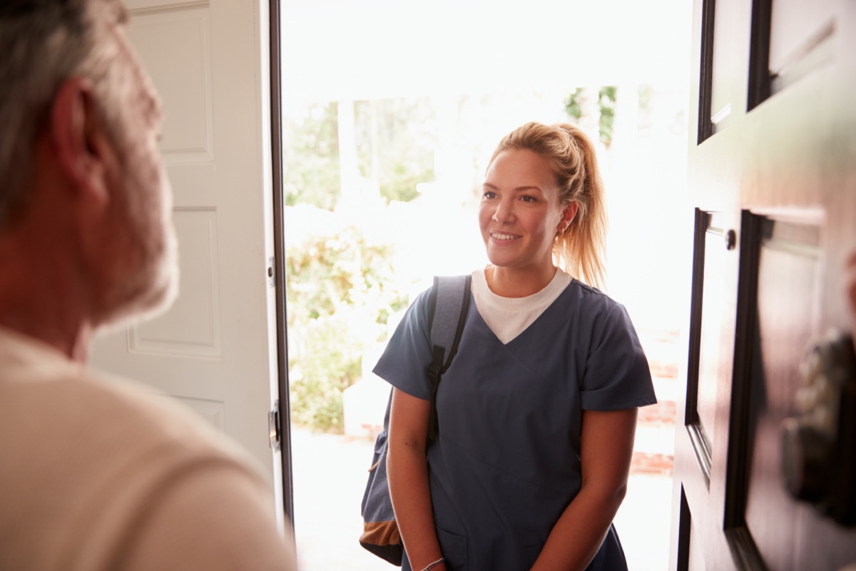 Senior man opening his front door to a female healthcare worker making a home health visit
