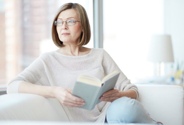 Charming mid age lady enjoying being at home and reading