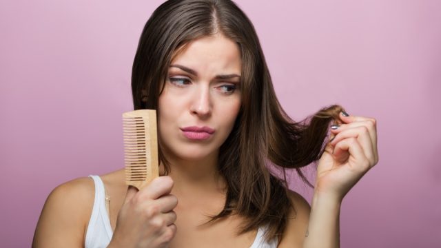 Woman brushing her hair with a wooden comb