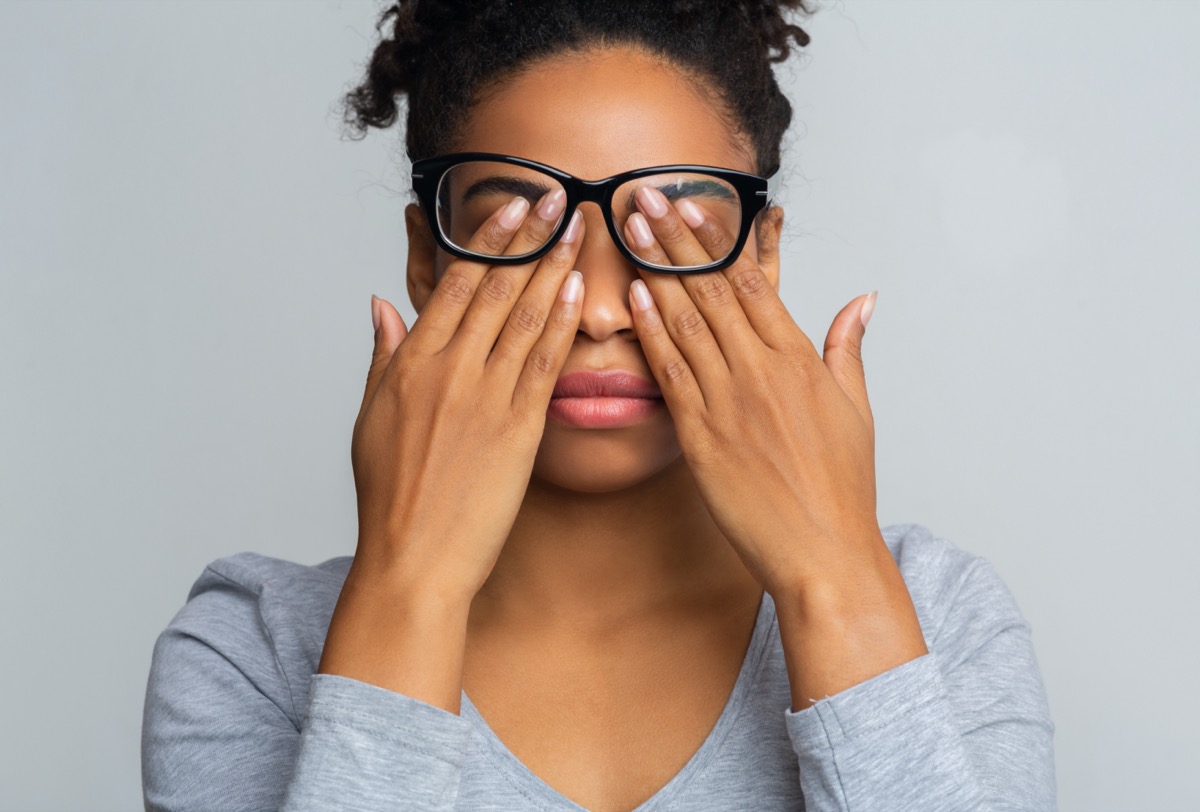 Woman in glasses rubs her eyes, suffering from tired eyes