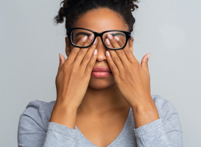 Woman in glasses rubs her eyes, suffering from tired eyes