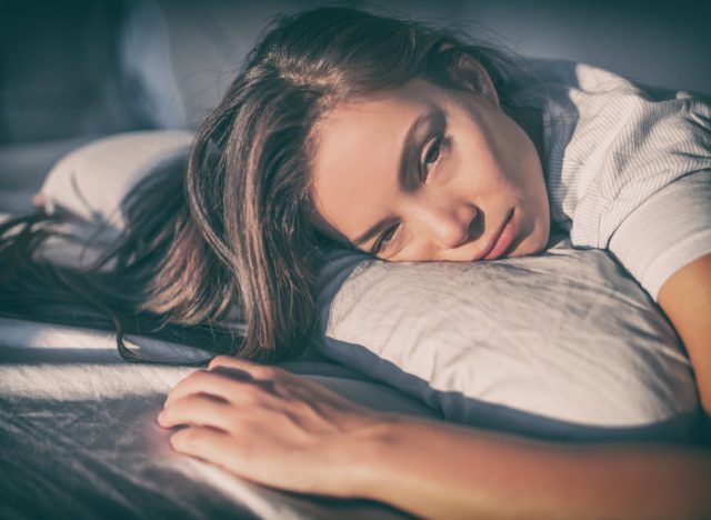 Tired woman lying in bed can't sleep late at night with insomnia