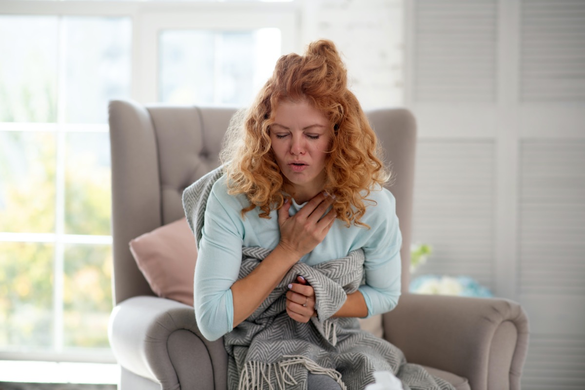 Curly woman feeling bad and suffering from strong cough while having flu