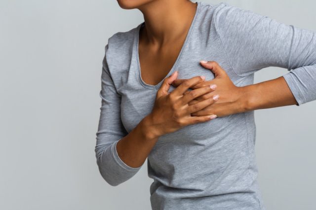 african woman feeling menstrual cyclic breast pain, touching her chest,