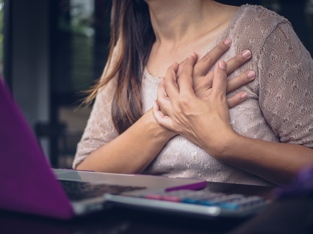 Woman touching breast and having chest pain after long hours work on computer