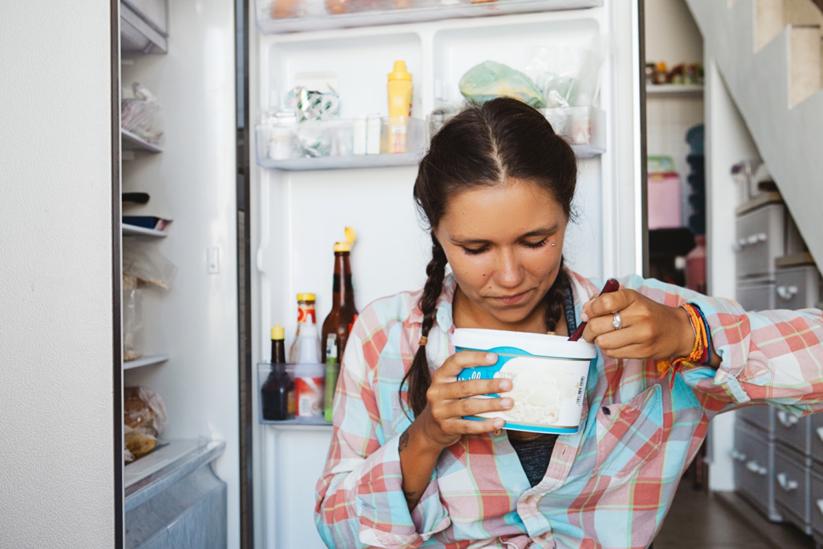 woman sitting next to the fridge, trying to keep diet and healthy eating