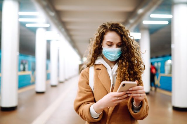 Girl in protective sterile medical mask with a phone at subway station