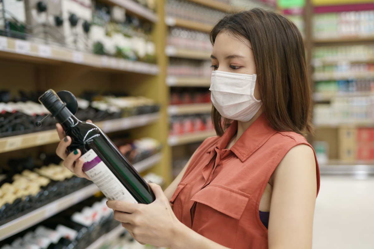Woman in medical protective mask panic buying wine