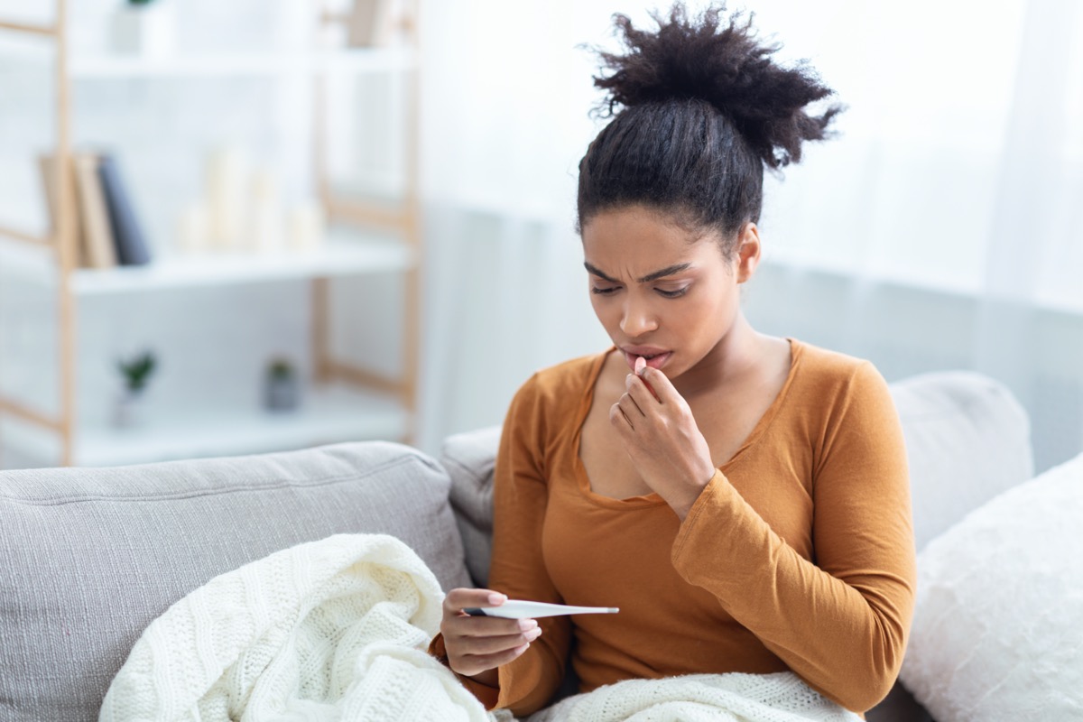 Lady Holding Thermometer Having Fever Measuring Body Temperature Sitting On Sofa At Home