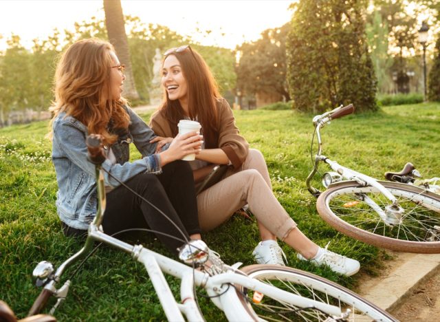 Image of two young beautiful women friends outdoors with bicycles in park.