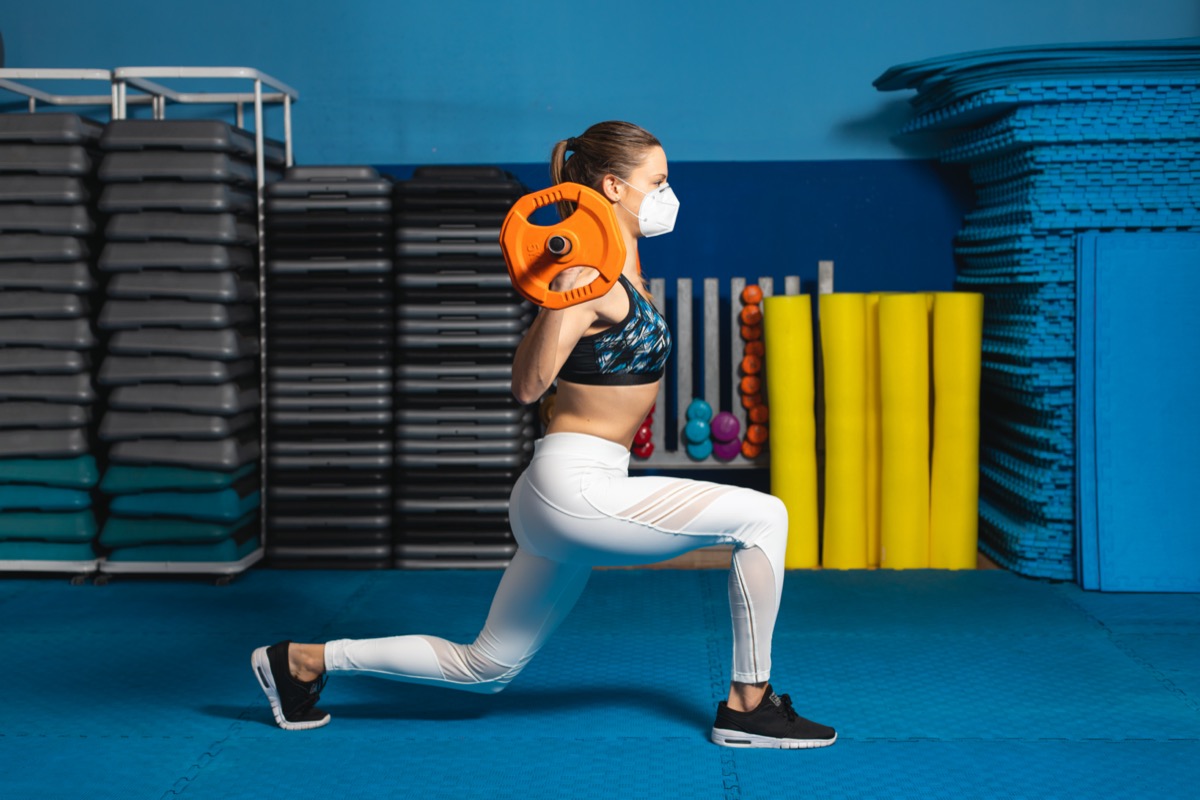 The Easiest Way To Live Longer, Says Science — Eat This Not That - Eat This, Not That 38 woman doing lunges at the gym wearing n95 face mask