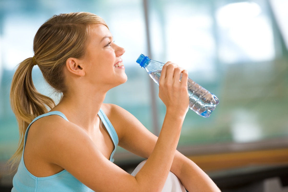 woman going to drink some water from plastic bottle after workout