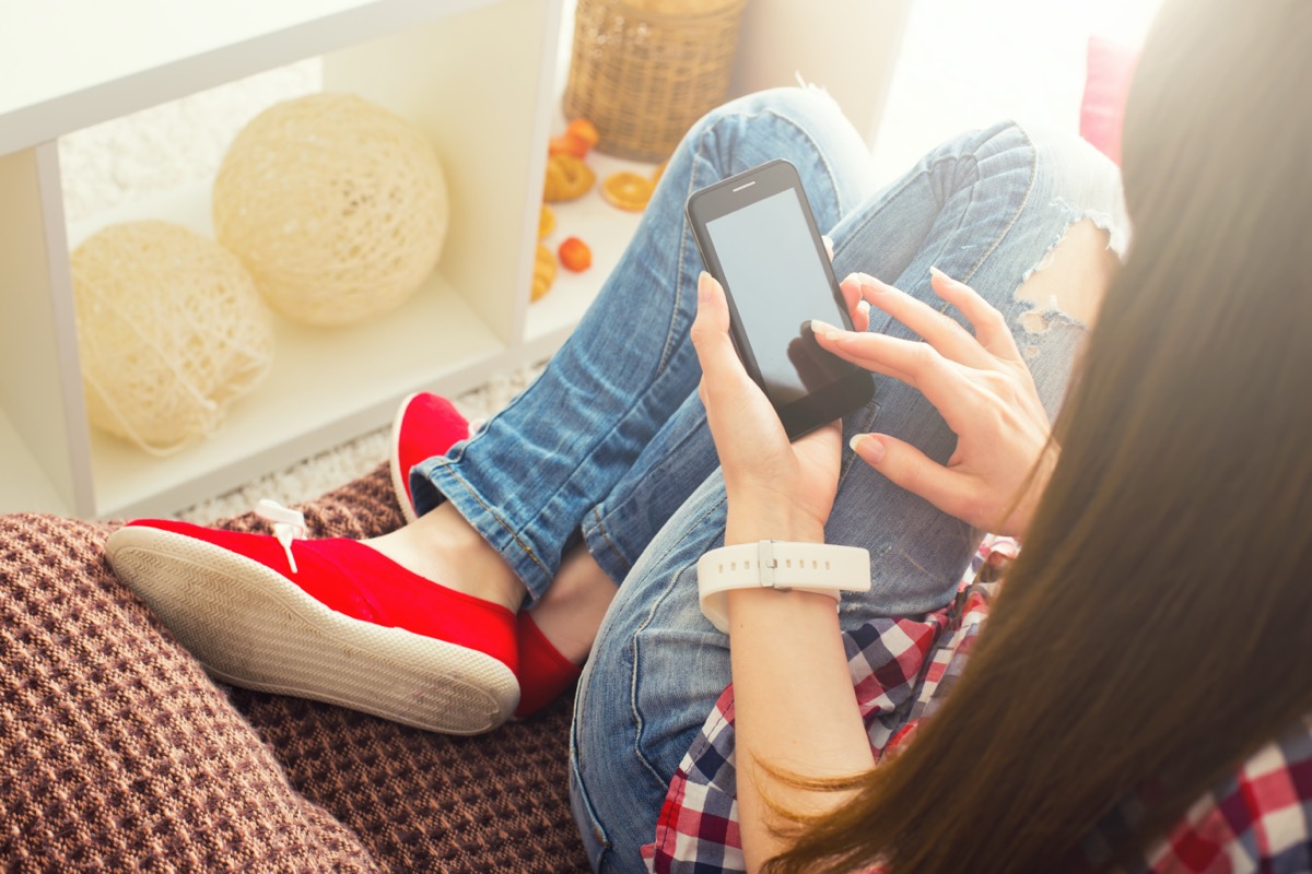 Woman at home relaxing on sofa couch reading email on mobile wifi connection