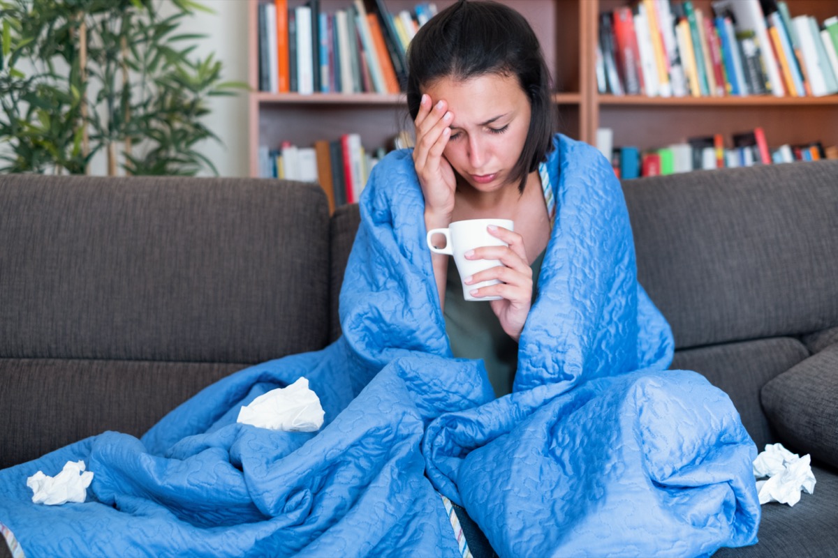 woman covered by a blanket on the sofa with high fever and flu